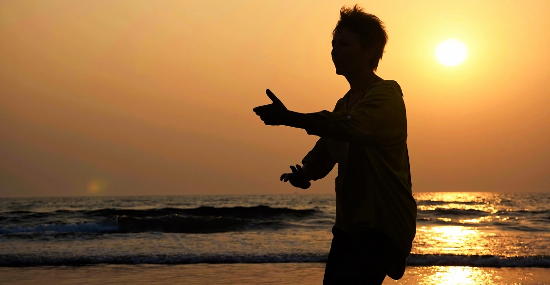 Silhouette of person practicing tai chi on the beach at sunset