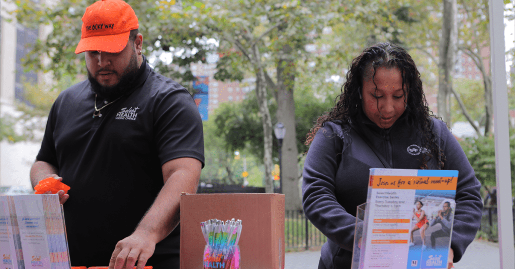 Photo of Demi Caceres and Ashley Carrillo displaying SelectHealth promo items on the table