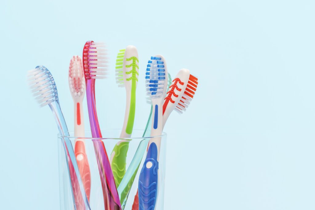Toothbrushes in glass cup on blue background close up, copy space.